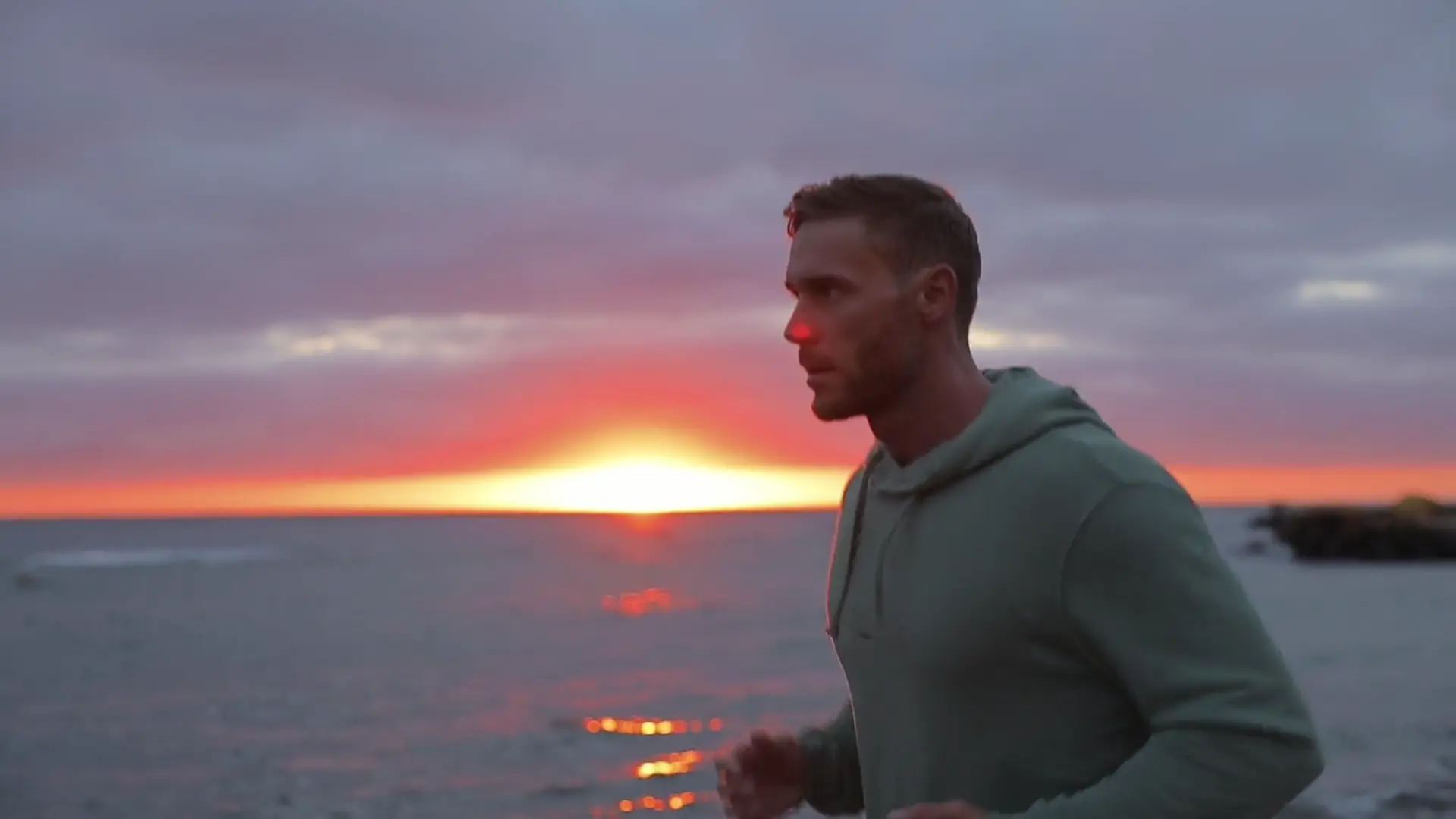 Man running along a beach at sunrise